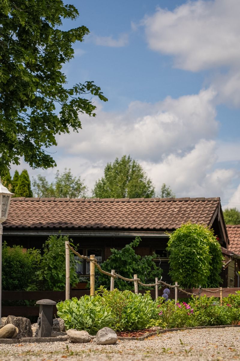 Gartenlaube mit Ziegeldach hinter einem Beet